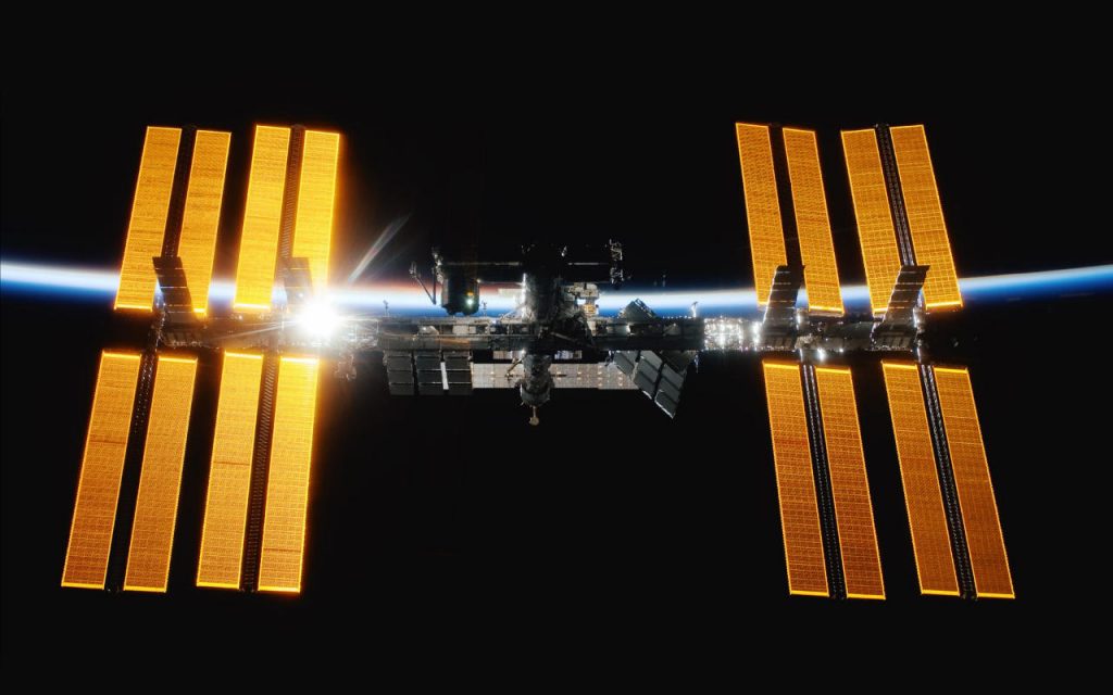 The International Space Station (ISS) in orbit around Earth. Backlit by the sun rising