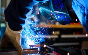 A welder making a weld with a blue flame