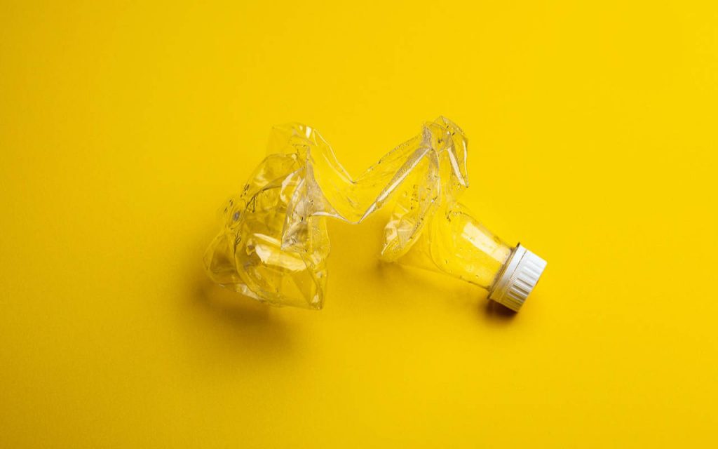 Crushed plastic bottle on a bright yellow background