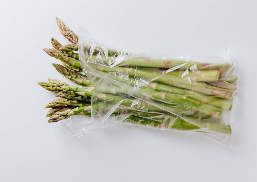 Long narrow bag filled with asparagus, shot on a white background (flatlay photograph)