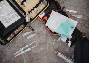 Medical plastics in a first aid kit – polythene medical packaging, plastic tubes and syringes – laid out on a concrete floor