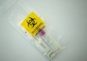 Printed polythene packaging for medical specimen sample. A yellow and black biohazard warning is printed on a clear polythene bag, with specimen visible inside