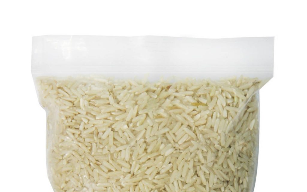 A product shot of a tear line polythene bag of uncooked rice. White background.