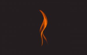 A single lick of flame on a reddish, off-black background.